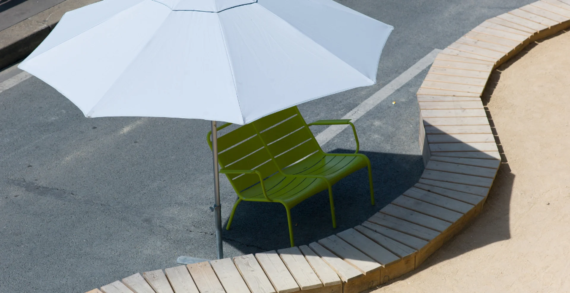Chaise longue à l'ombre d'un grand parasol blanc, ambiance balnéaire de Paris Plages près des appart'hôtels Yuna
