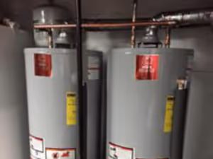 Two gray water heaters with red labels.