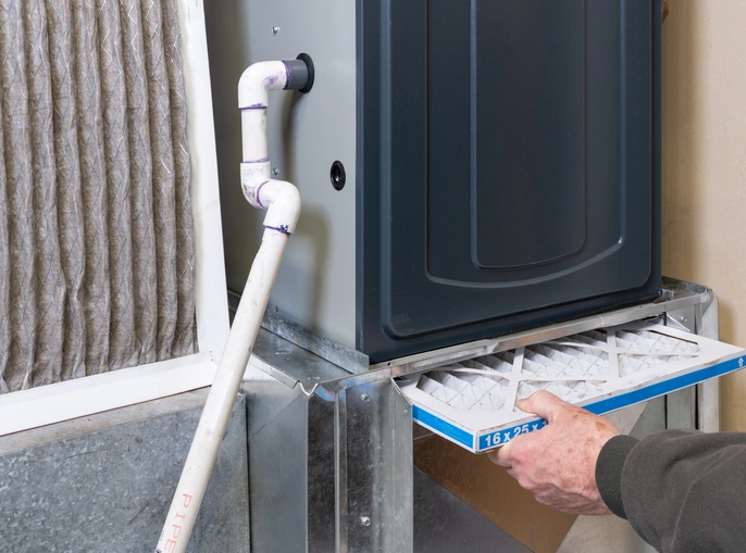 A person replaces an air filter in a furnace. 