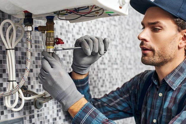 Plumber tightening a pipe connection on a boiler.