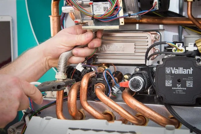 Hand servicing internal components of a Vaillant boiler.