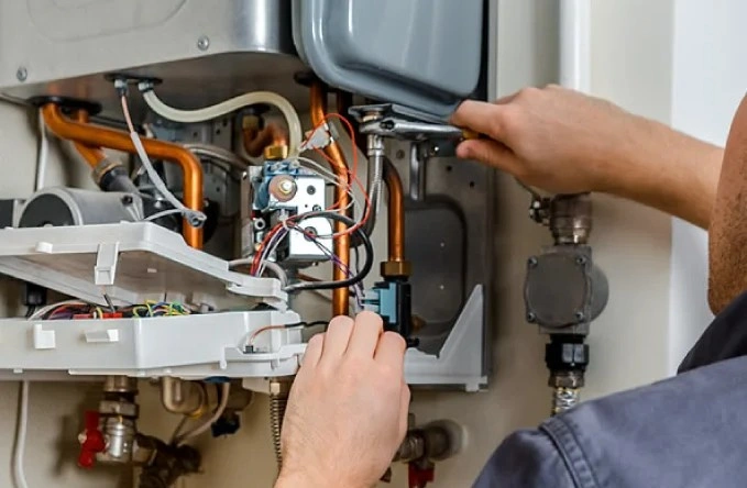 Technician tightens pipes inside a boiler.