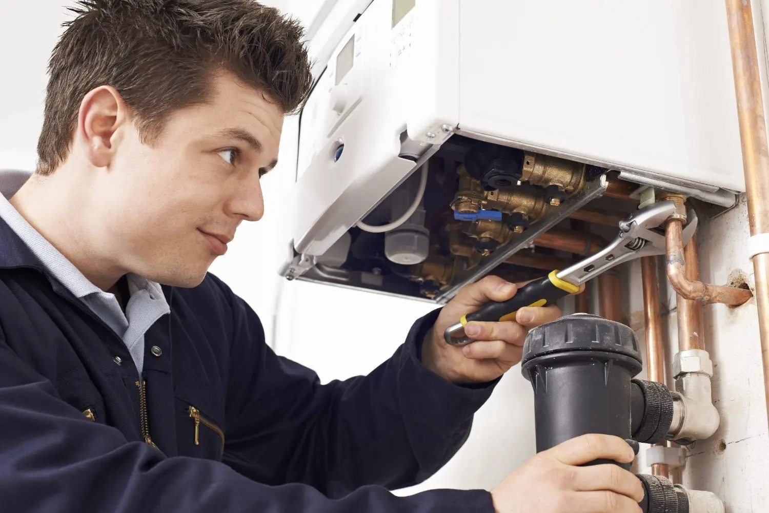 A technician fixing a wall-mounted boiler or furnace.