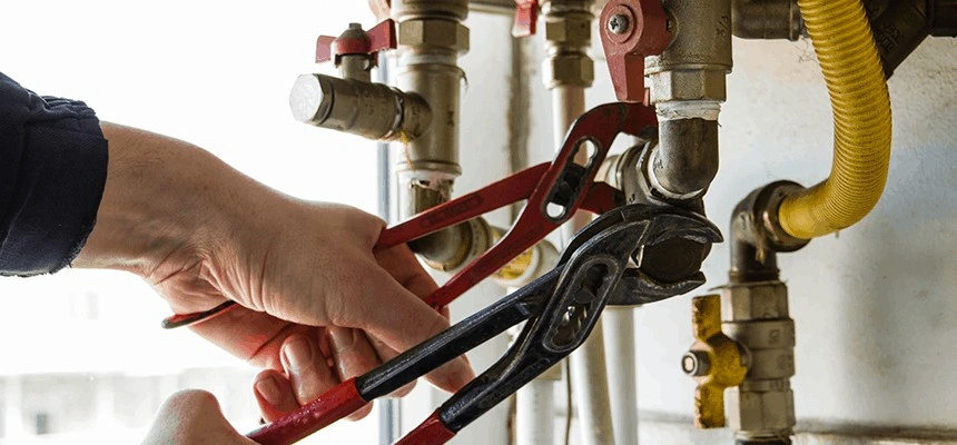 Using wrenches to tighten boiler pipes.