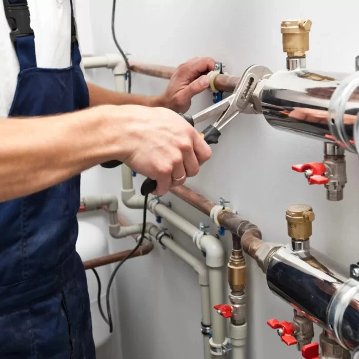 Technician tightening copper pipes with wrench.