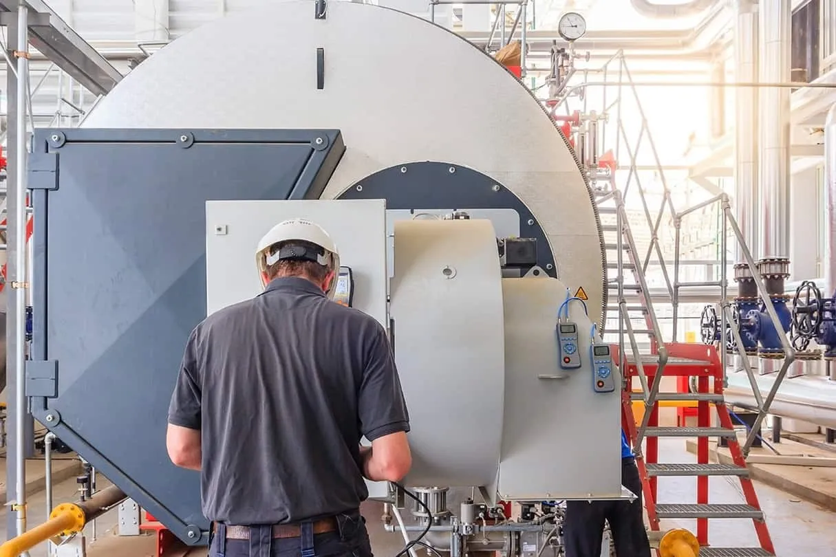Engineer inspecting large industrial boiler machinery.