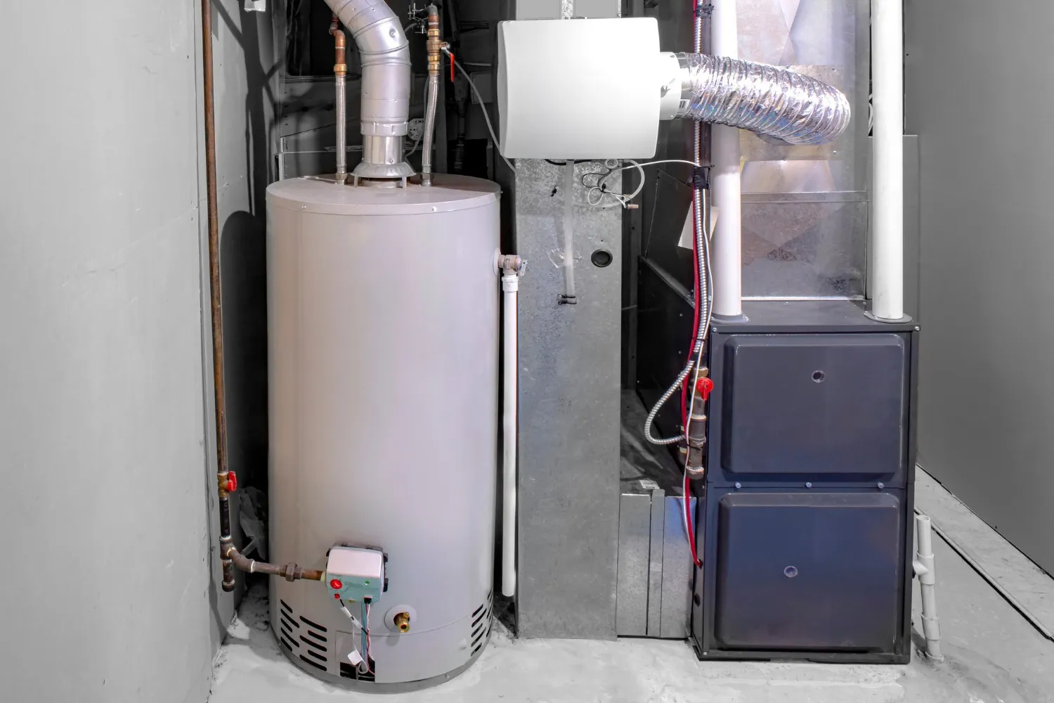 A clean, well-maintained utility area featuring a large, grey water heater tank standing next to a dark grey furnace unit.