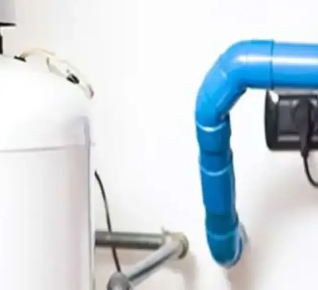 Smiling worker in a blue uniform and cap inspecting a water heater.