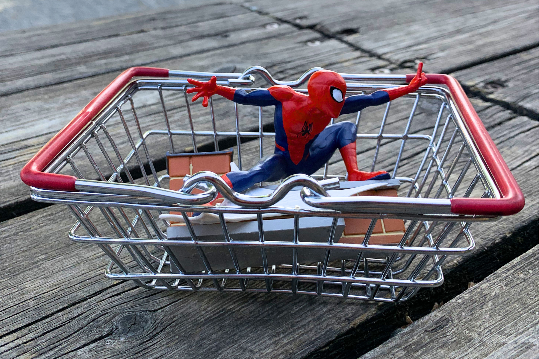 A miniature shopping basket with a Spider-Man toy inside