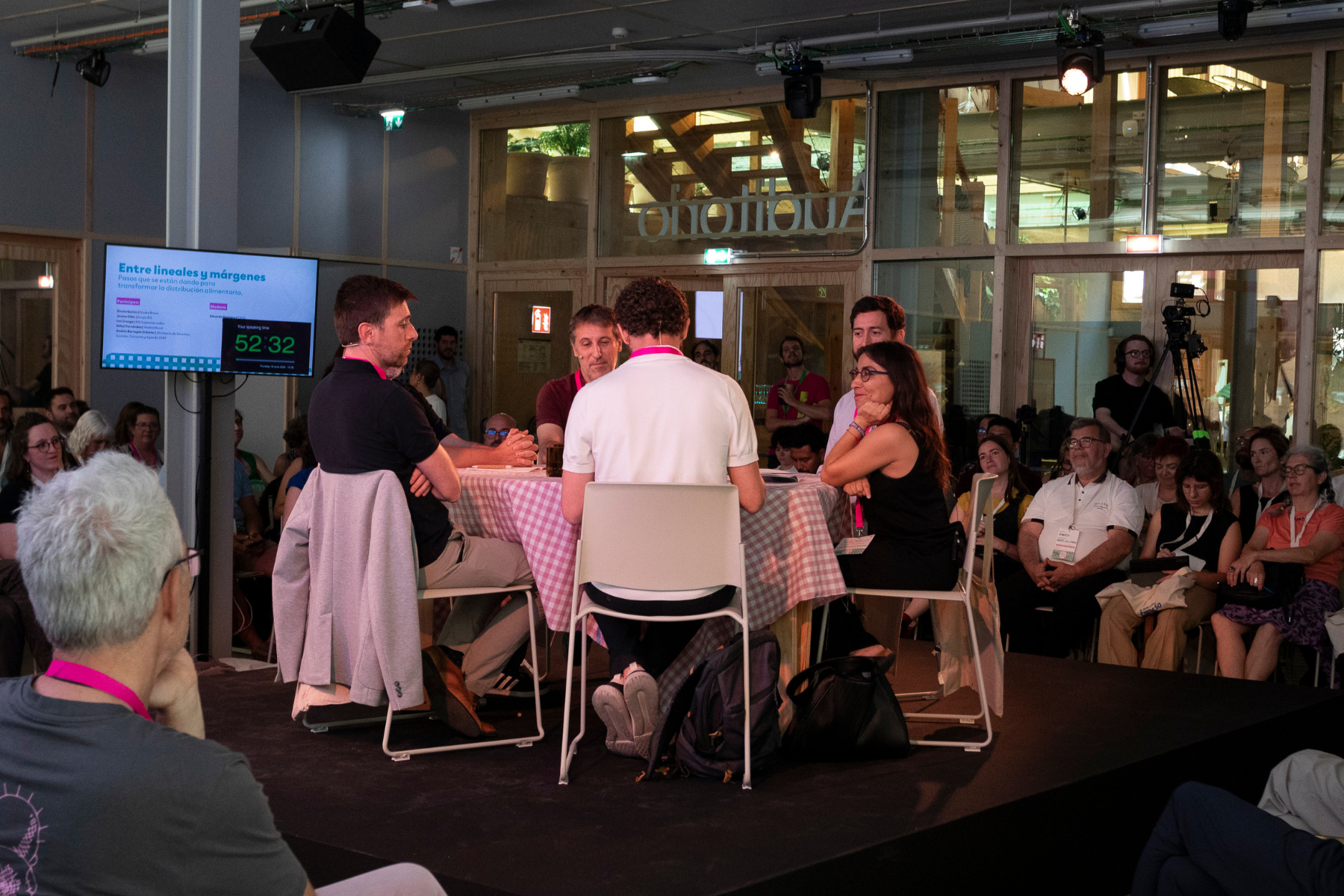 Zinnia sitting at a table alongside five other speakers, surrounded by an audience 