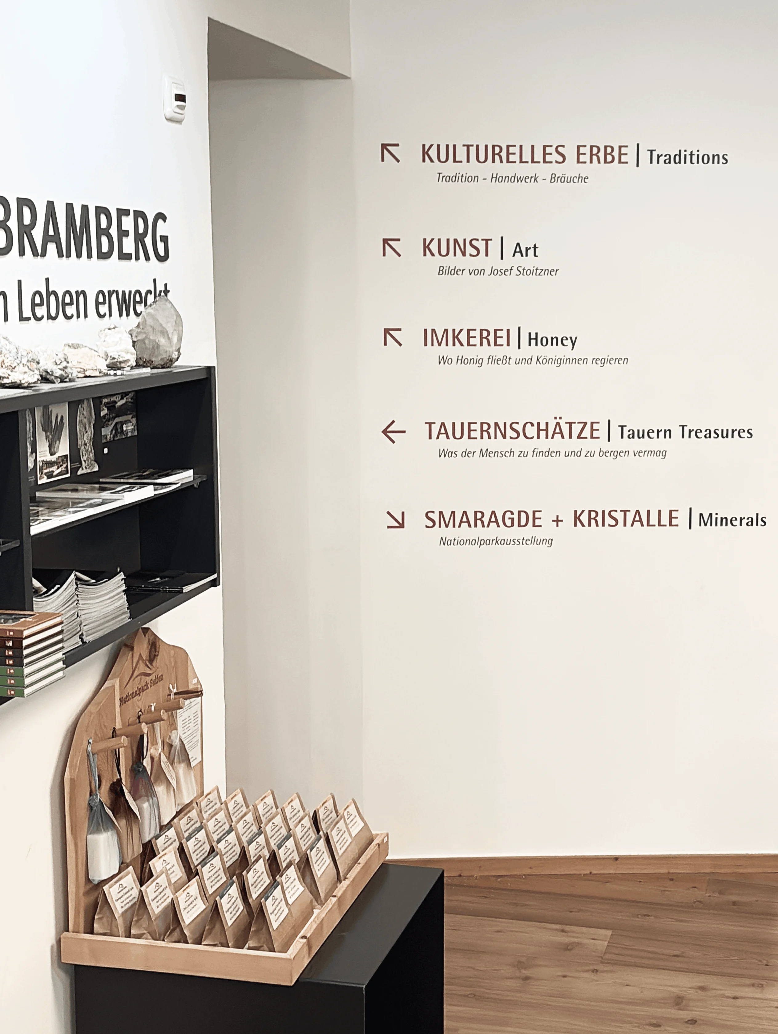 Wegweiser im Museum Bramberg mit Pfeilen und Themen: Kulturelles Erbe, Kunst, Imkerei, Tauernschätze und Smaragde + Kristalle.