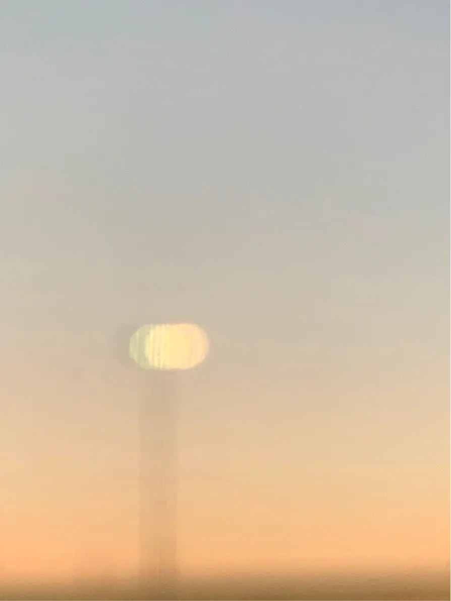 Blurred street lamp against a pale orange sunset sky