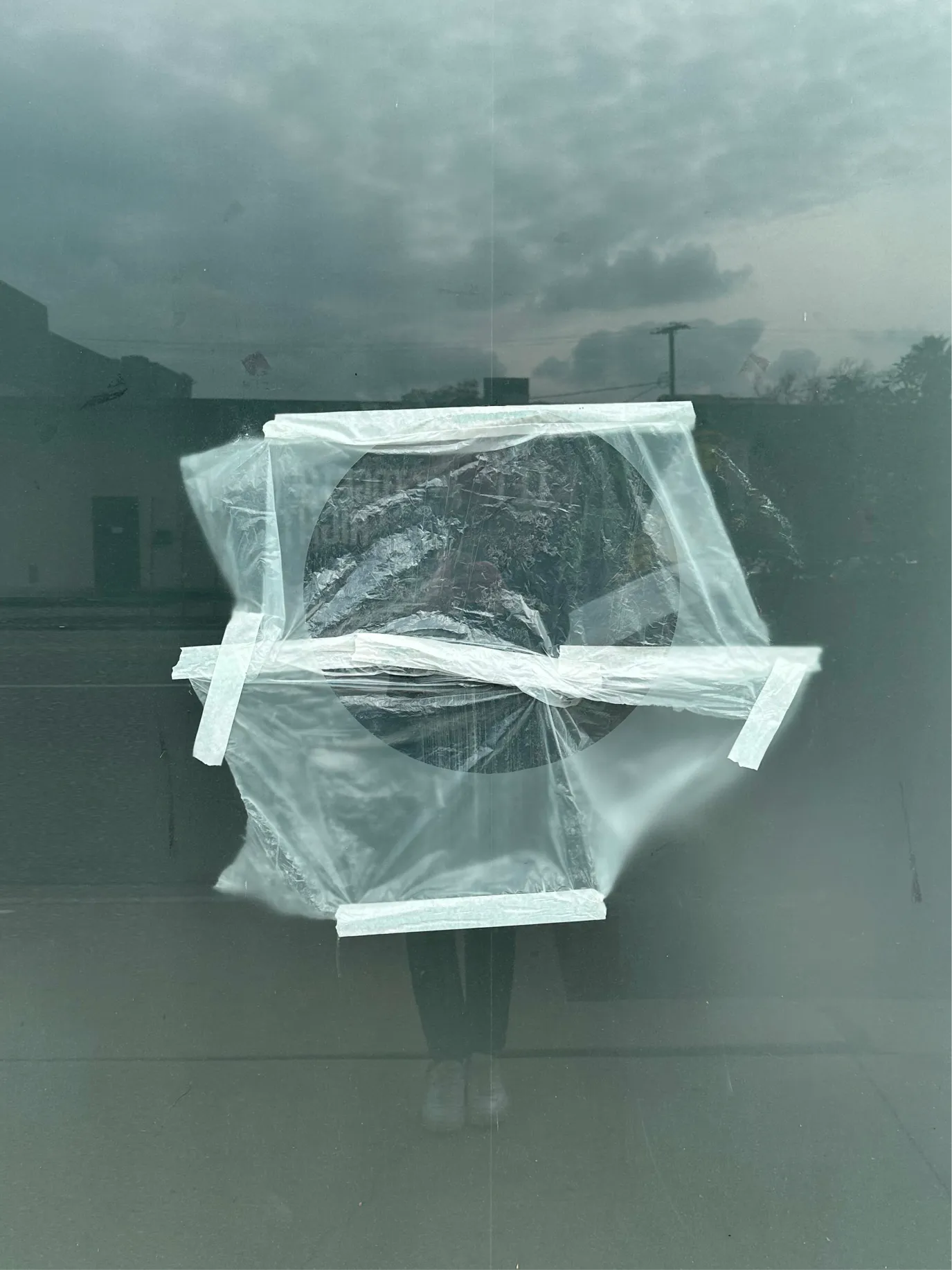 Object wrapped in clear plastic and tape against a misty window