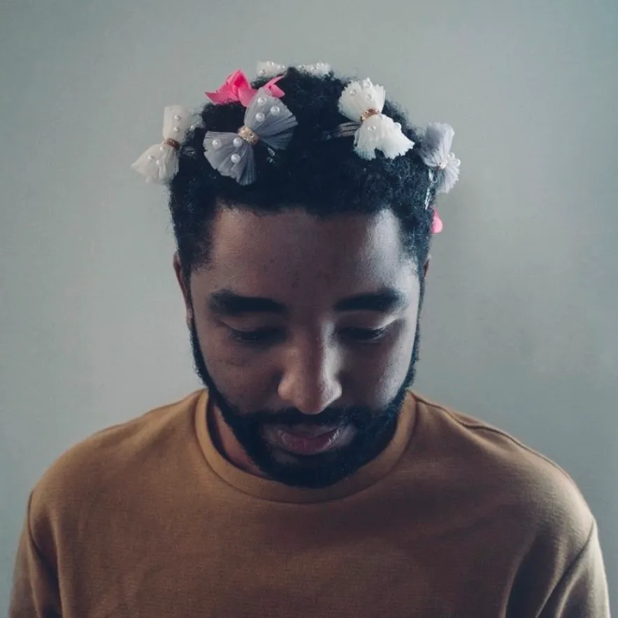 Man wearing a flower crown, looking down
