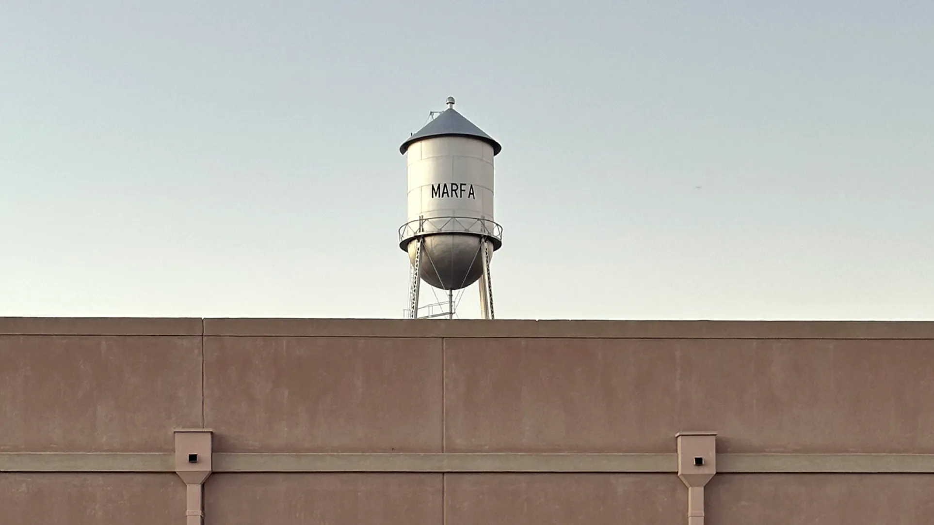 Water tower rising above a flat rooftop at dusk