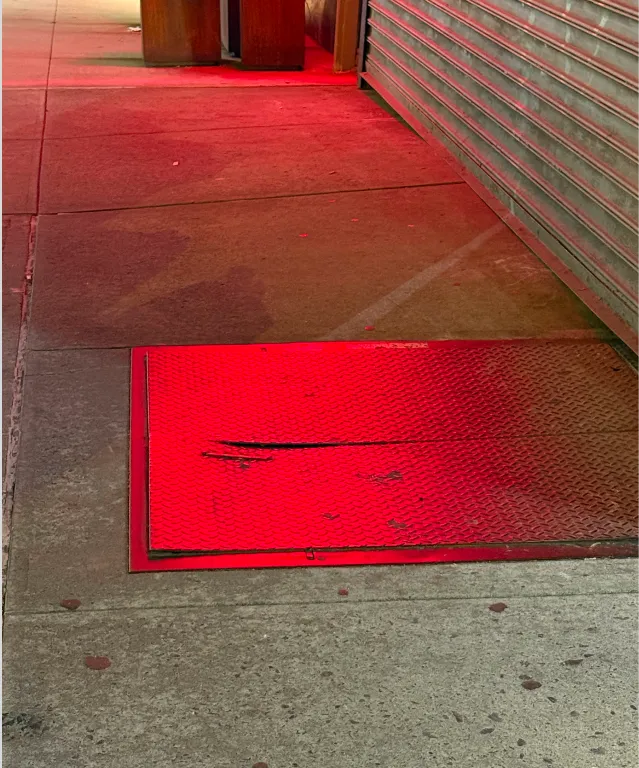 Red light glowing on a sidewalk at night