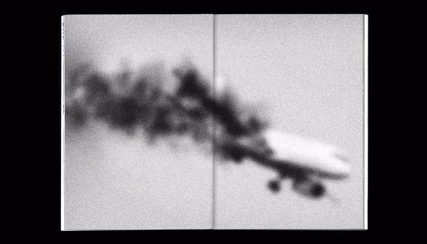 Black and white image of an airplane trailing dense black smoke, depicted across two pages of an open book or magazine.