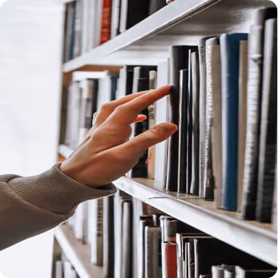 A hand reaching out to grab a library book off of a shelf.