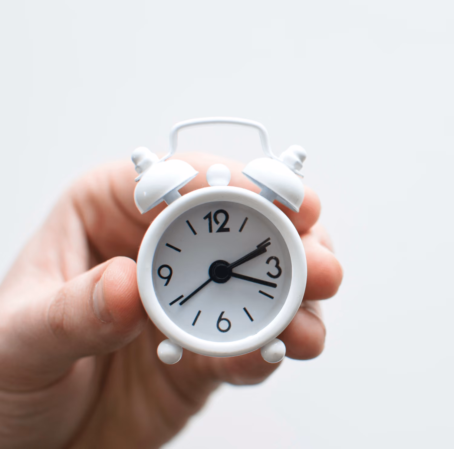 hand holding a small old alarm clock