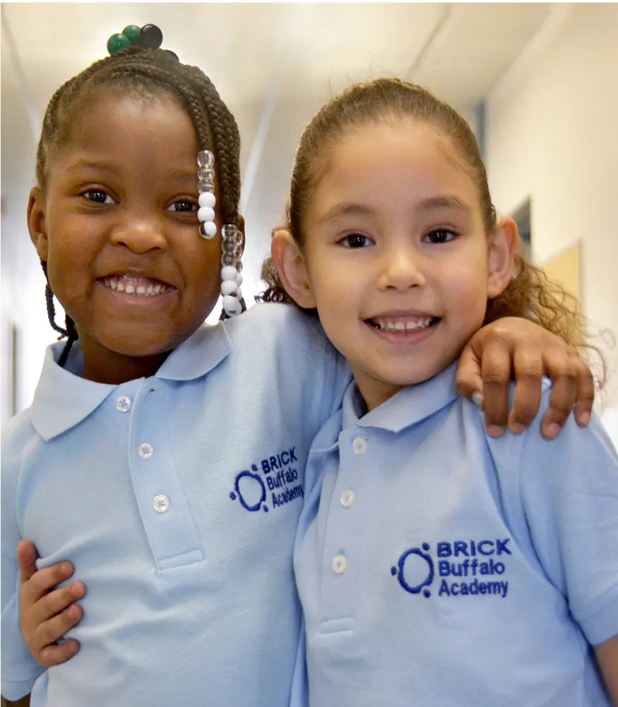 Dos niñas con su uniforme escolar sonriendo a la cámara