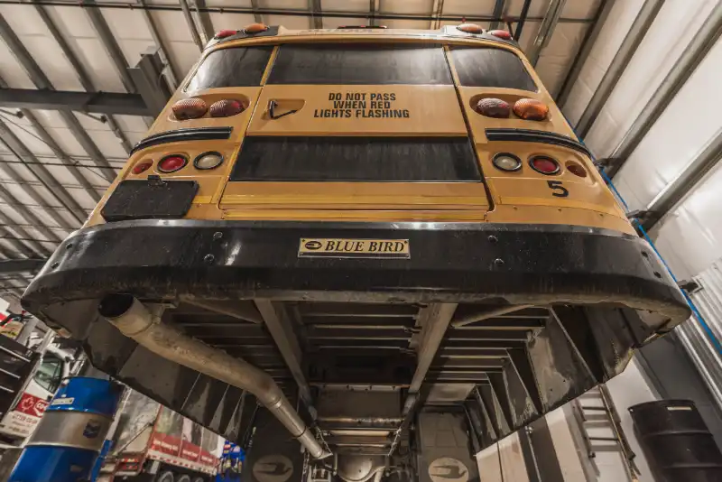 Yellow coach navigates muddy construction path, panel reads “SCHOOL BUS,” unit 5269 awaits off-road service.