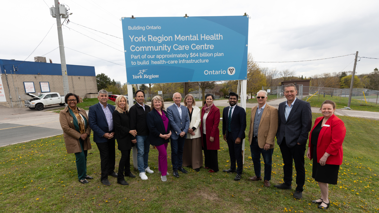 Group of individuals standing on grass in front of a sign.