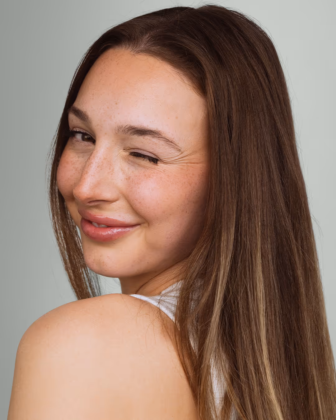 A woman looking over her shoulder and winking at the camera after a lip flip treatment.