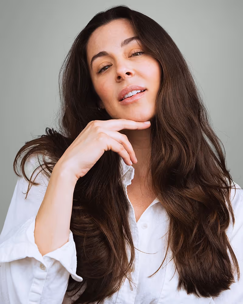 A dark-haired woman posing with a hand under her chin after a Dysport treatment.