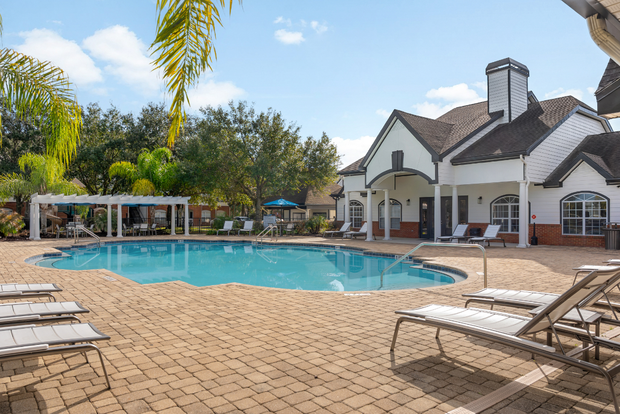 Exterior of the community clubhouse and pool house, located next to the resort-style pool with lounge chairs at The Finley in Jacksonville, FL.