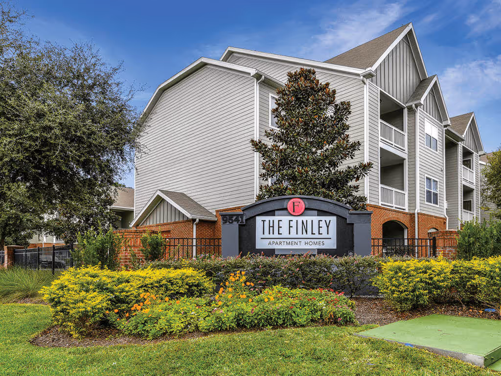 Exterior entrance sign for The Finley Apartment Homes, with brick accents and lush landscaping in Jacksonville, FL.