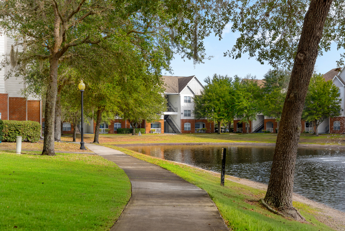 Scenic view of the community lake with apartment buildings and a clear blue sky at The Finley in Jacksonville, FL.