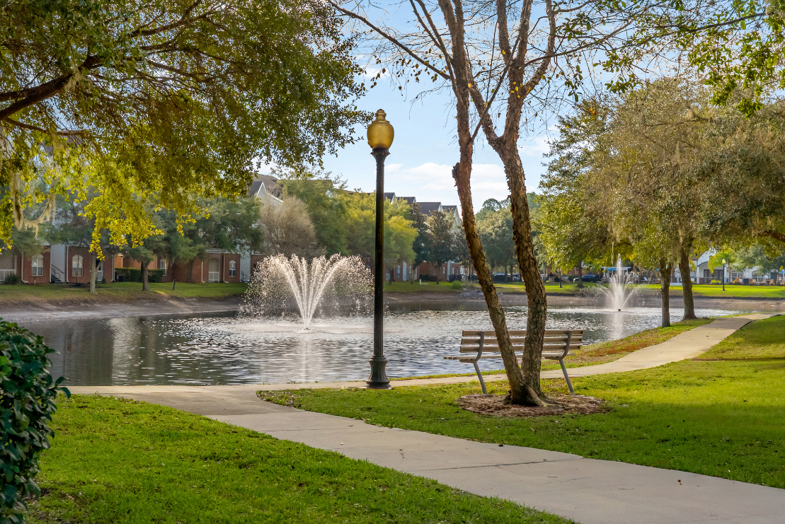 Scenic community lake with a fountain, surrounded by apartment buildings, showcasing a beautiful view at The Finley in Jacksonville, FL.