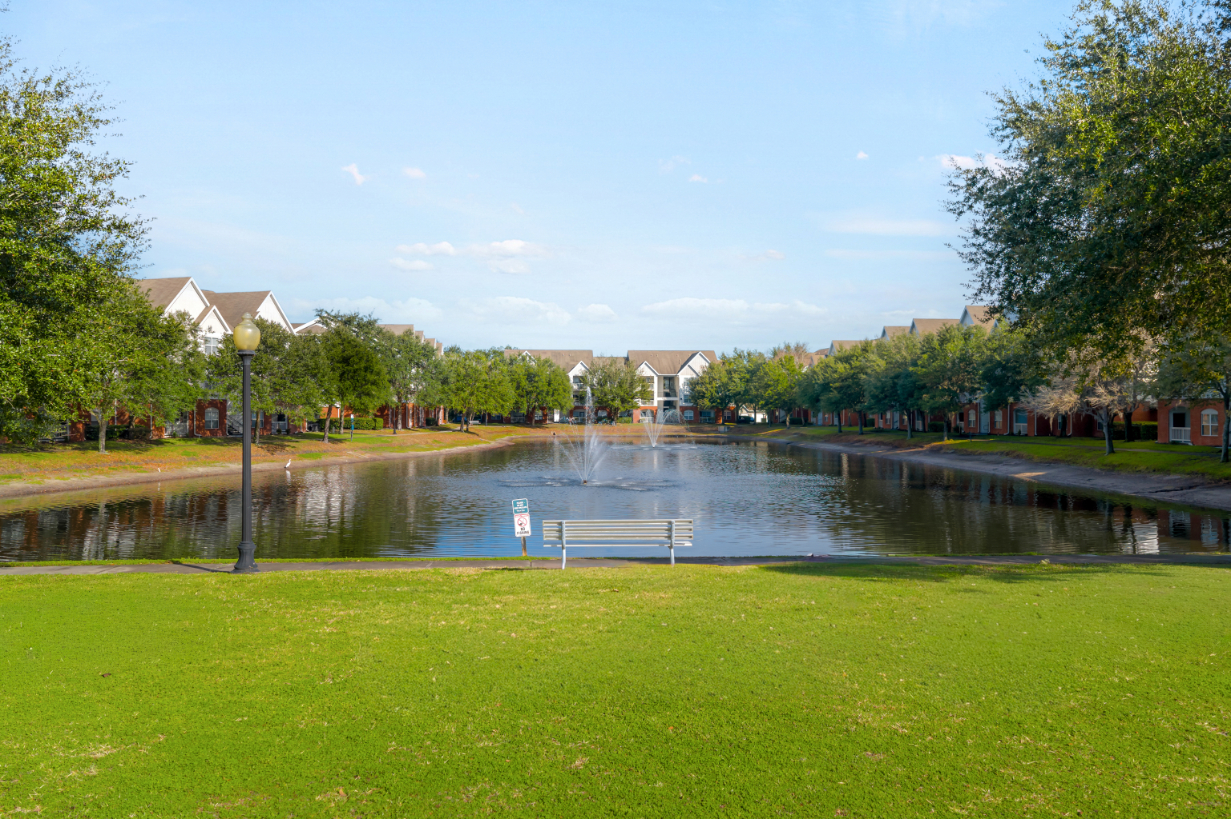 Scenic community lake with a fountain, surrounded by apartment buildings, showcasing a beautiful view at The Finley in Jacksonville, FL