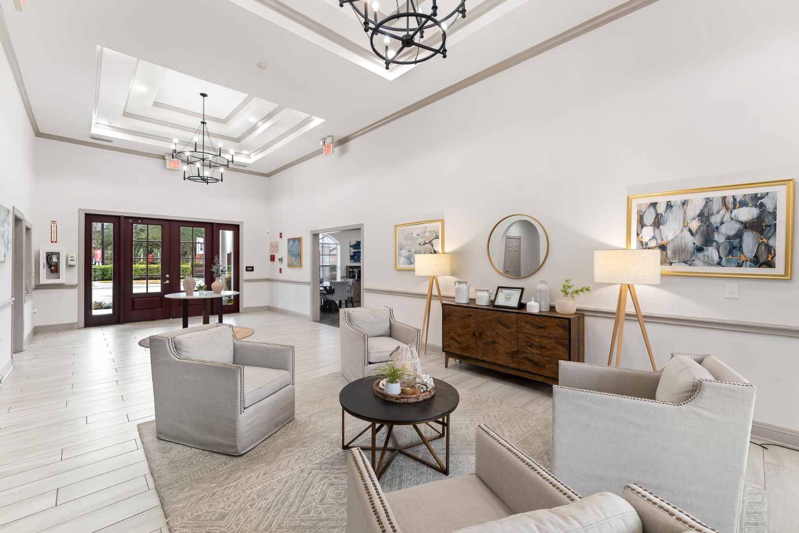 Elegant resident clubhouse lobby with comfortable seating, decorative mirrors, and modern chandeliers at The Finley in Jacksonville, FL