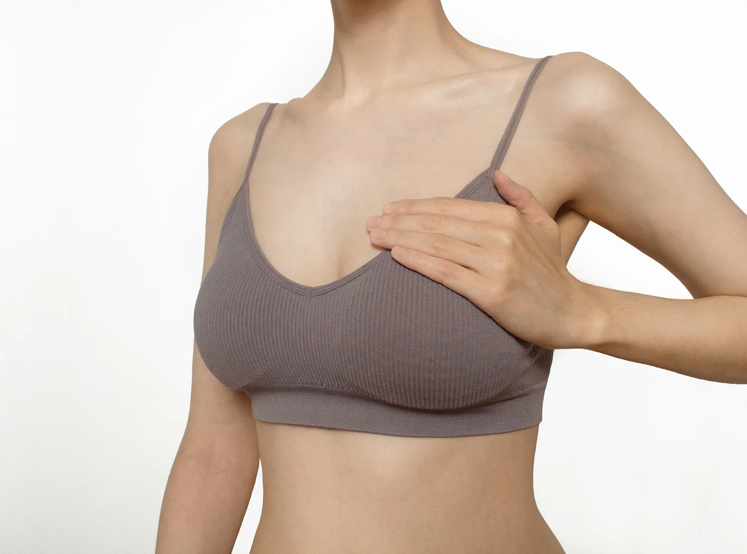 A woman in a bra top is holding her breast.