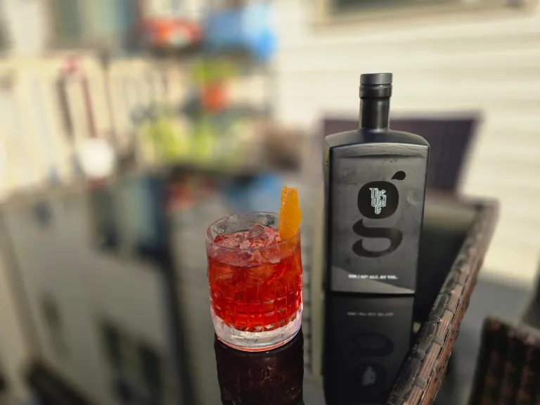 A negroni cocktail sitting next to a bottle of The Old G gin
