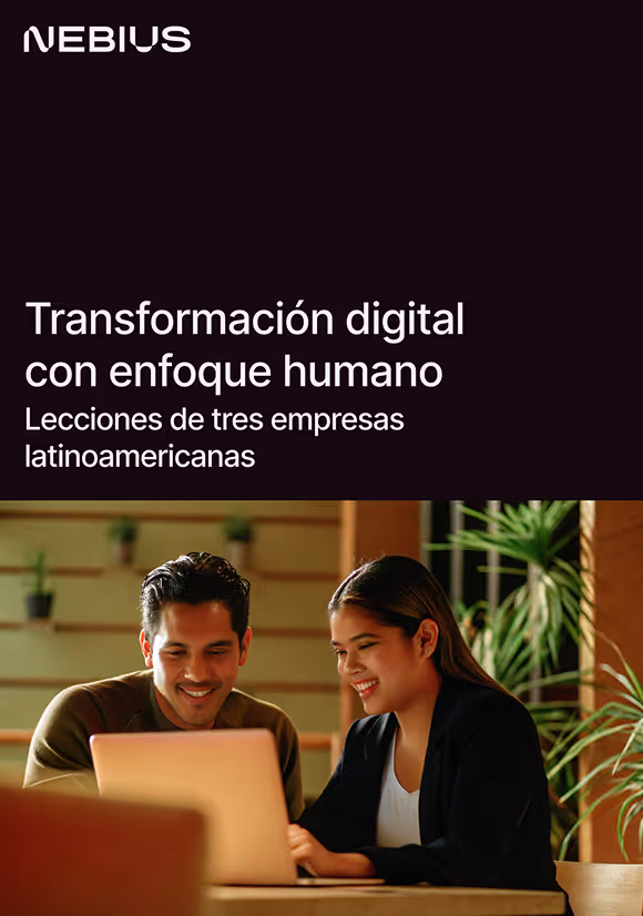 Two professionals smiling and working together on a laptop in a modern office space with plants.