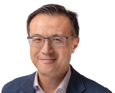 Middle-aged man wearing glasses and a blue blazer smiling against a white background.