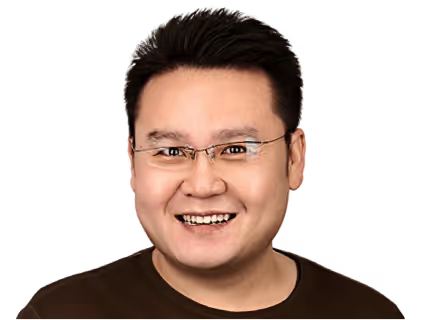 Smiling man with short black hair wearing glasses and a dark brown shirt.