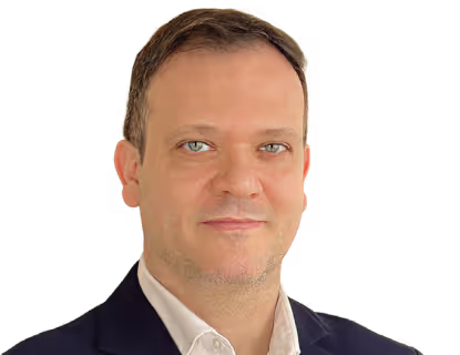 Portrait of a middle-aged man with short brown hair, blue eyes, wearing a white shirt and dark blazer.