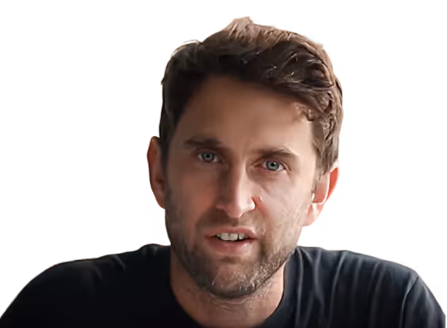 Portrait of a man with short brown hair and light facial hair wearing a dark shirt, looking toward the camera.