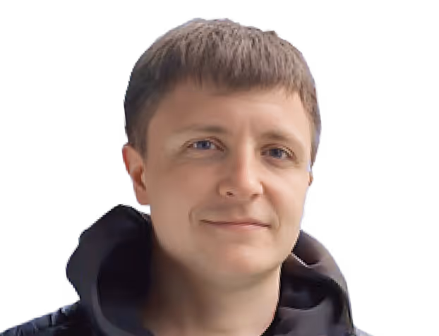 Portrait of a young person with short light brown hair wearing a black hoodie, smiling slightly.