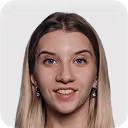 Portrait of a smiling young woman with long dark hair and hoop earrings, against a black background.