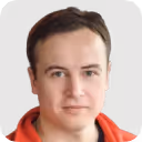 Portrait of a man with short brown hair and light skin wearing a red and black jacket.