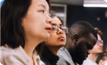People of diverse backgrounds attentively listening in a classroom or seminar setting.