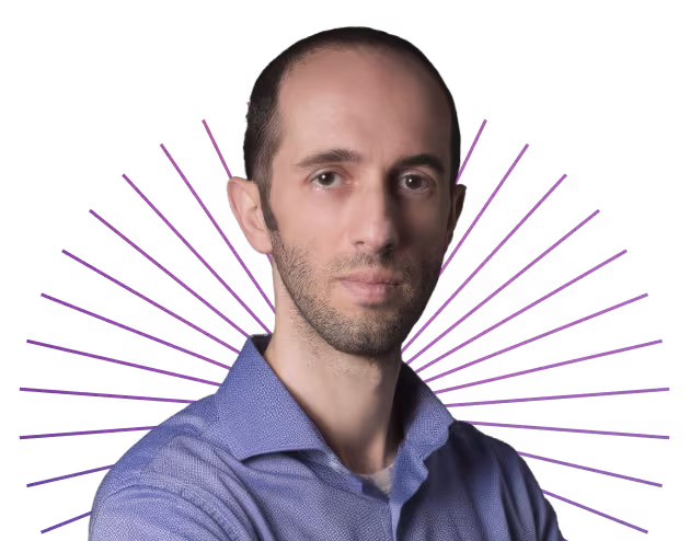 Man with short dark hair and blue shirt against a black background with purple radiating lines.