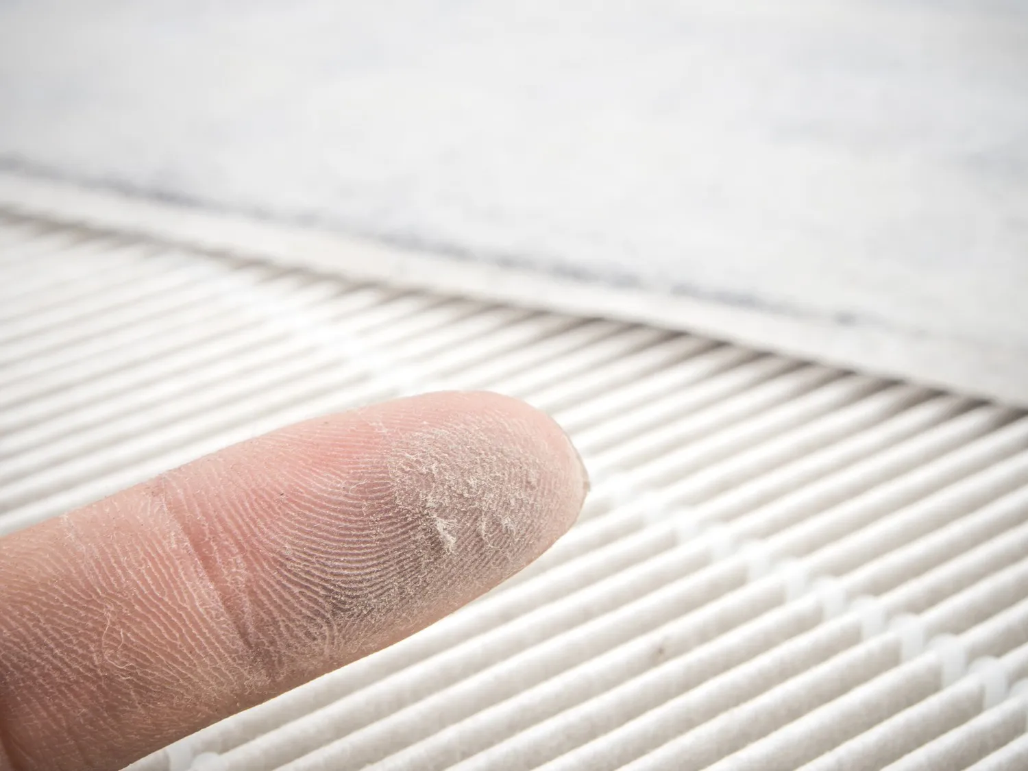 Finger showing accumulated dust from an air filter.