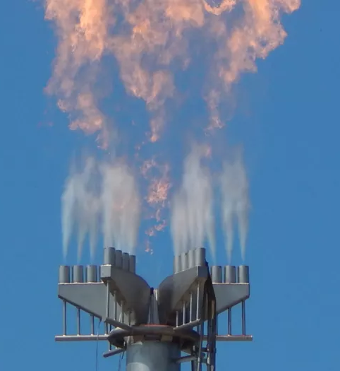 Close-up of nViro-XSR flare in operation with visible steam-assisted flame against blue sky.