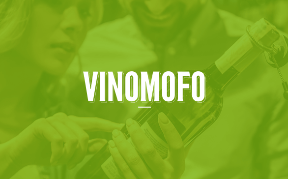 Two people examining a wine bottle, with the word VINOMOFO in bold white letters overlayed.