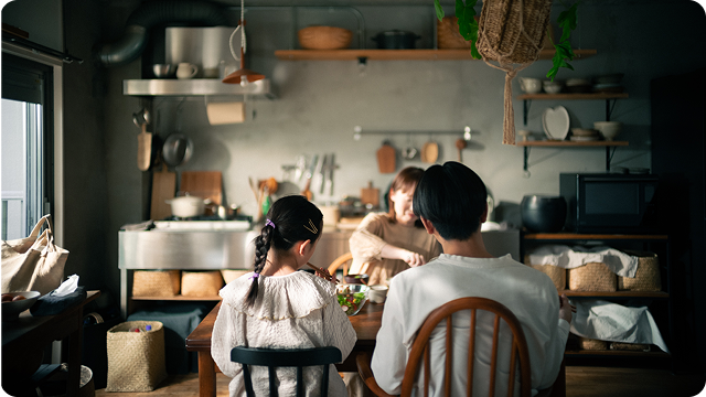 A family of three enjoying a meal together at a wooden table in a cozy kitchen.